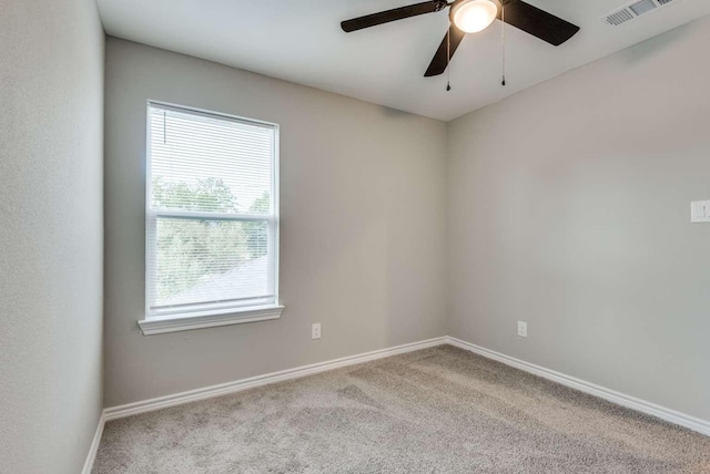 carpeted empty room featuring baseboards, visible vents, and a ceiling fan