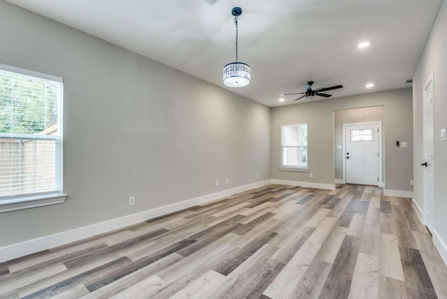 interior space with light wood finished floors, ceiling fan with notable chandelier, baseboards, and recessed lighting