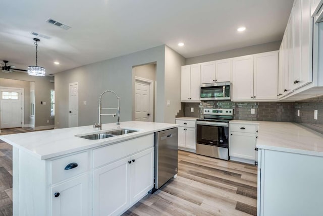 kitchen featuring a kitchen island with sink, a sink, visible vents, light wood-style floors, and appliances with stainless steel finishes