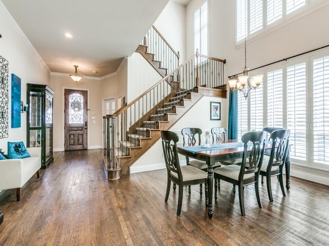 dining area with wood finished floors, baseboards, ornamental molding, stairs, and a chandelier