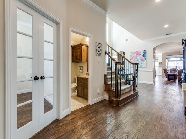 interior space with wood finished floors, visible vents, arched walkways, stairs, and french doors