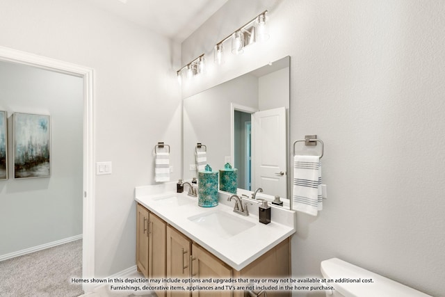 bathroom featuring toilet, double vanity, baseboards, and a sink