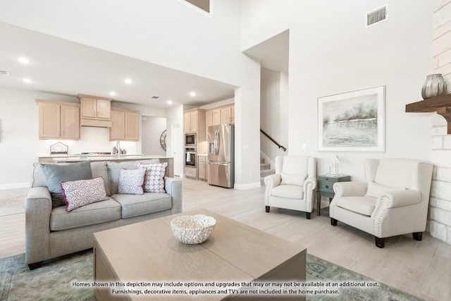 living room featuring baseboards, visible vents, stairs, light wood-style floors, and recessed lighting