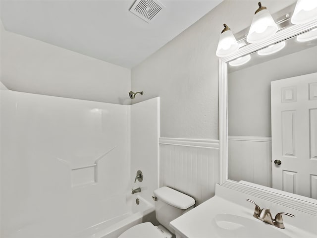 bathroom featuring shower / tub combination, toilet, vanity, visible vents, and wainscoting