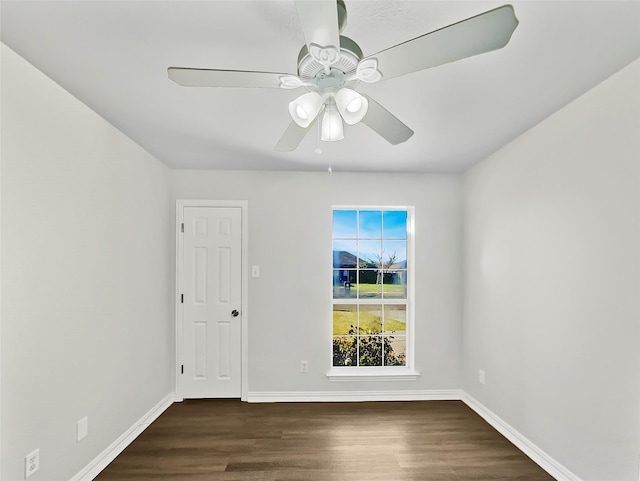 unfurnished room with dark wood finished floors, a ceiling fan, and baseboards