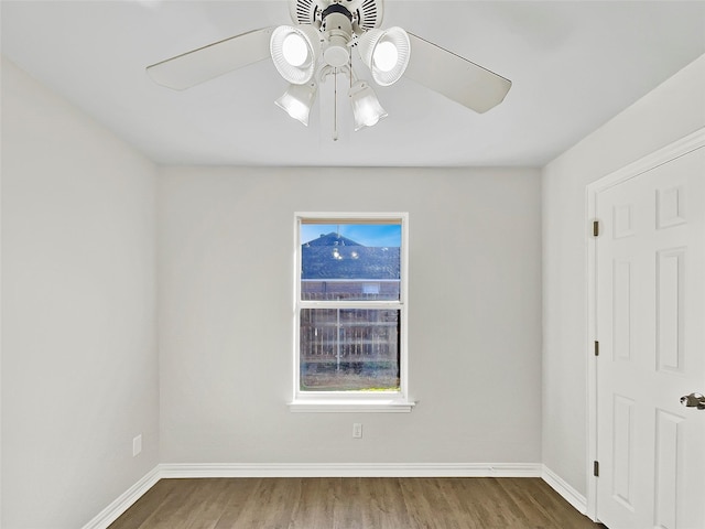 empty room with a ceiling fan, baseboards, and wood finished floors