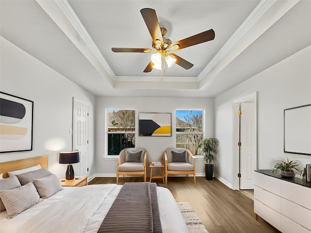 bedroom with ornamental molding, a raised ceiling, baseboards, and wood finished floors