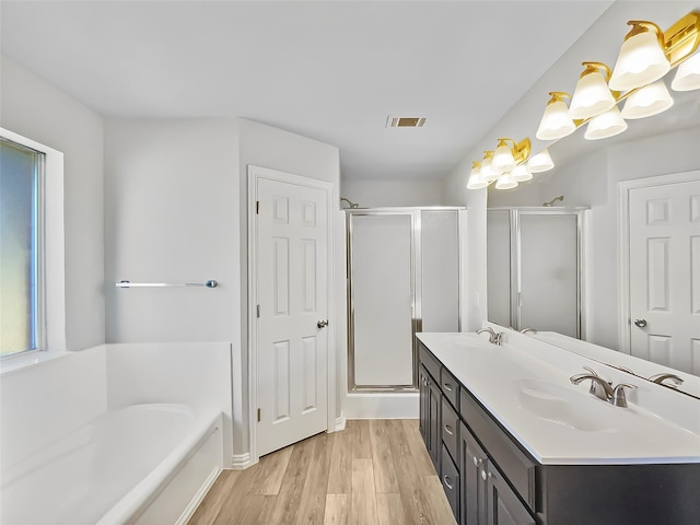 bathroom with a stall shower, visible vents, a sink, and wood finished floors