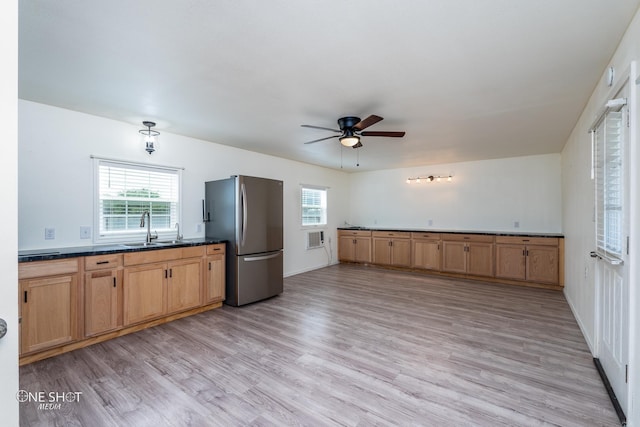 kitchen featuring ceiling fan, a sink, light wood-style floors, freestanding refrigerator, and dark countertops