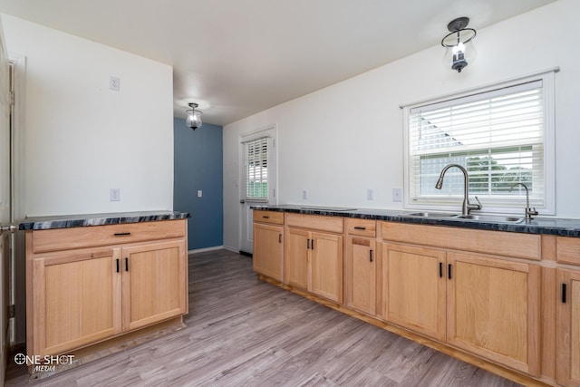 kitchen with light brown cabinets, dark countertops, and a sink