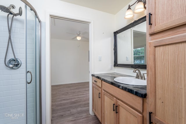 bathroom featuring a ceiling fan, a shower stall, vanity, and wood finished floors