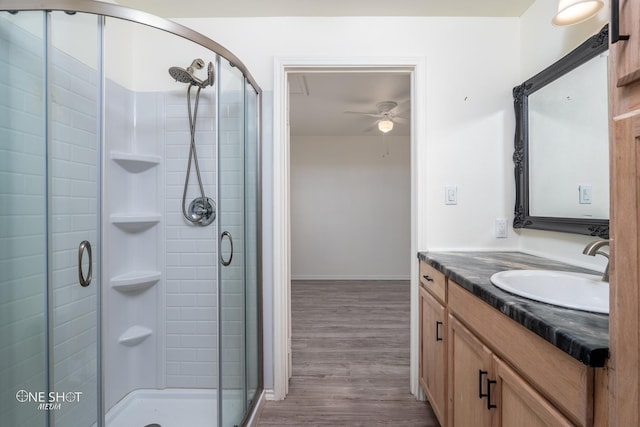 full bathroom with a ceiling fan, a stall shower, vanity, and wood finished floors