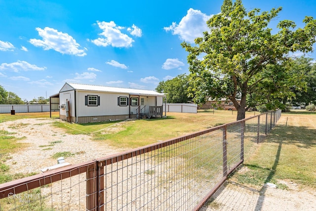 rear view of house with a fenced backyard, metal roof, and a yard