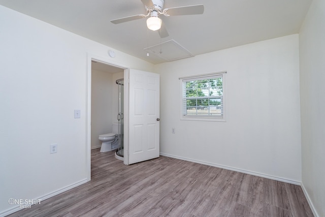 spare room with attic access, a ceiling fan, baseboards, and wood finished floors