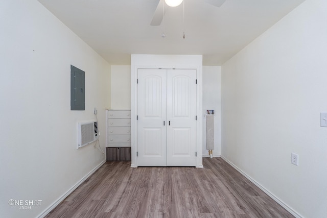 unfurnished bedroom with electric panel, baseboards, a closet, and wood finished floors