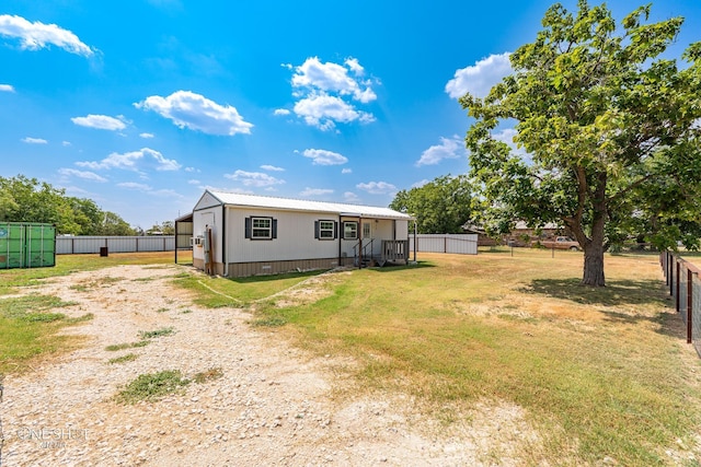 rear view of property featuring metal roof, fence, and a lawn