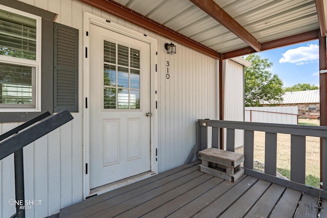 view of exterior entry featuring fence and a deck