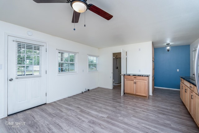 kitchen with dark countertops, light wood-style floors, ceiling fan, and baseboards