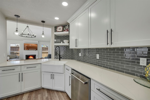 kitchen with light wood-style flooring, a sink, white cabinetry, a lit fireplace, and dishwasher