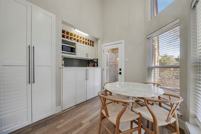 dining room featuring a towering ceiling and light wood-style flooring