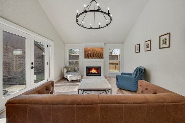 living room featuring lofted ceiling, a lit fireplace, and wood finished floors