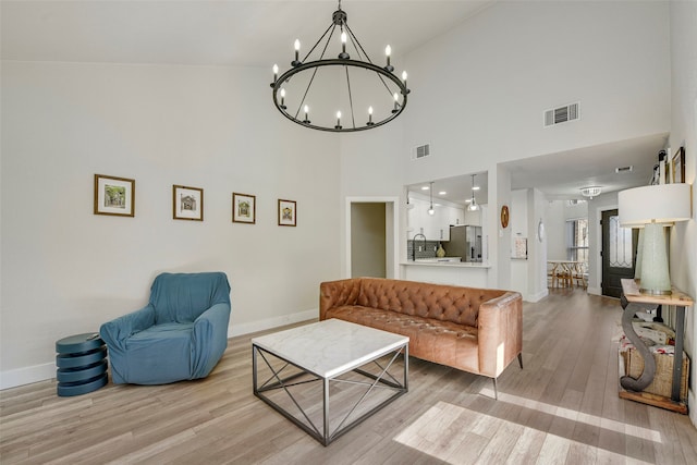 living area with light wood-style floors, baseboards, visible vents, and a chandelier