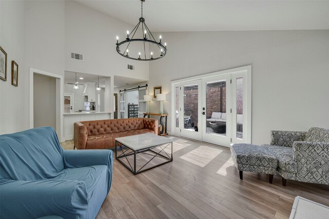 living room featuring light wood-style flooring, visible vents, french doors, and a barn door