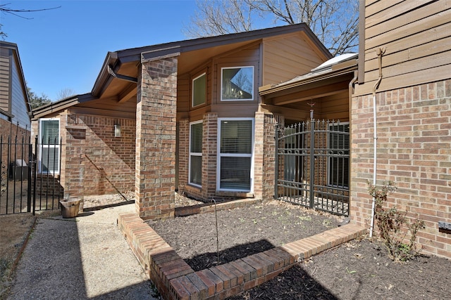 doorway to property with brick siding and fence