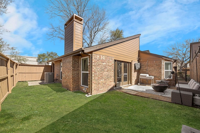 rear view of property featuring a chimney, brick siding, a fire pit, and a fenced backyard