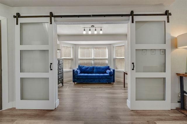 interior space with a barn door, baseboards, and wood finished floors