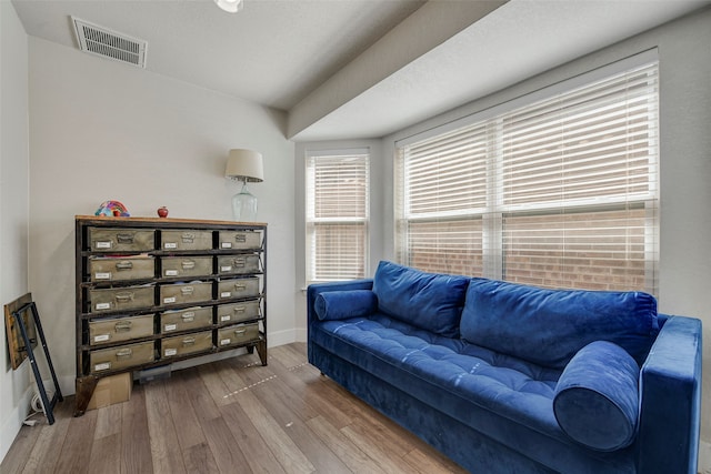 living area with baseboards, visible vents, and wood finished floors