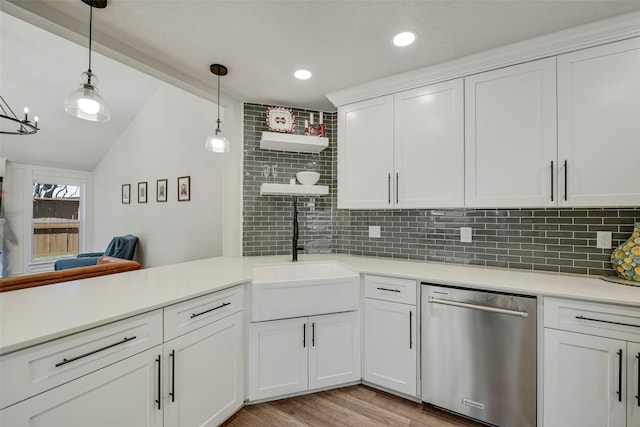 kitchen with a sink, white cabinets, light countertops, stainless steel dishwasher, and decorative backsplash