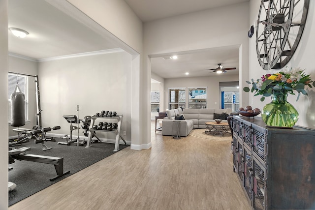 exercise room with ornamental molding, ceiling fan, baseboards, and wood finished floors