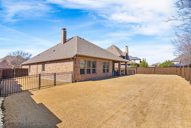 back of house featuring brick siding, a patio, a chimney, and a fenced backyard