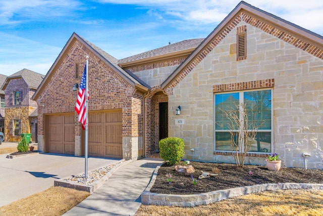 view of front facade with a shingled roof, concrete driveway, stone siding, an attached garage, and brick siding