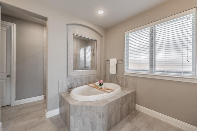 full bath with baseboards and a bath