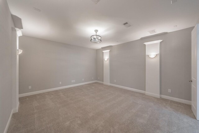 spare room featuring light carpet, visible vents, and baseboards