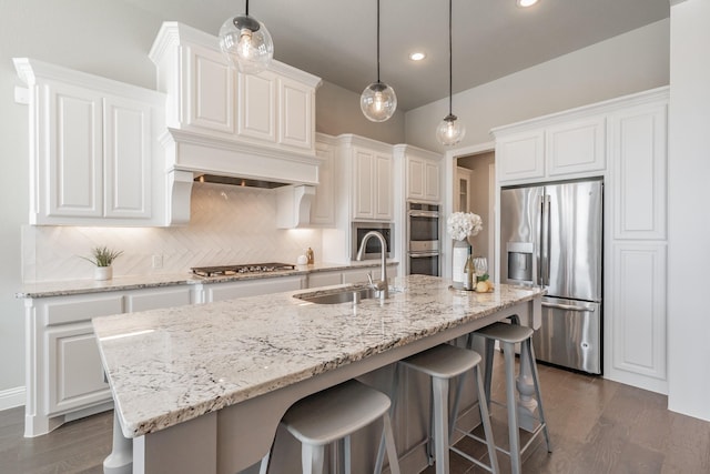 kitchen featuring stainless steel appliances, dark wood-type flooring, a sink, white cabinets, and backsplash