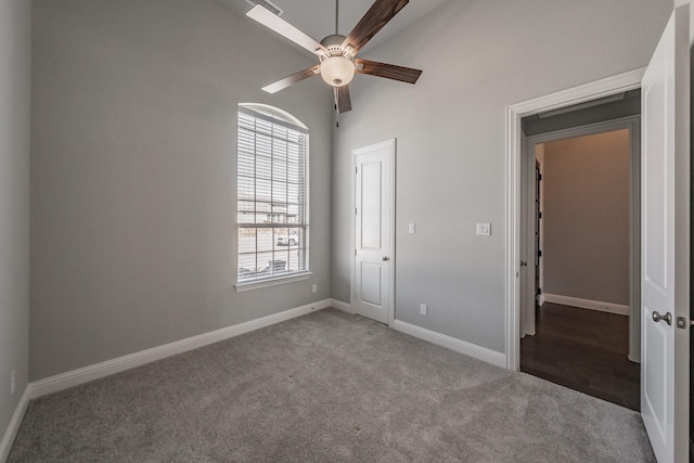 carpeted spare room featuring a high ceiling, baseboards, and a ceiling fan