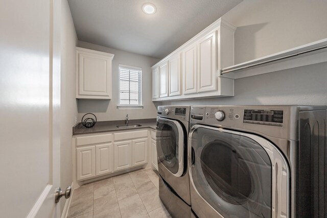 laundry room featuring cabinet space, a sink, washing machine and clothes dryer, and light tile patterned floors