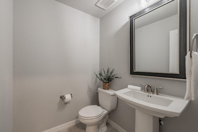 half bath with baseboards, visible vents, a sink, and toilet