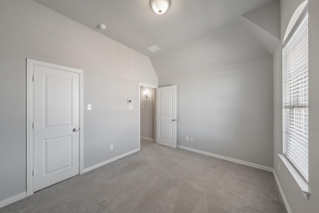 unfurnished bedroom with vaulted ceiling, light carpet, and baseboards