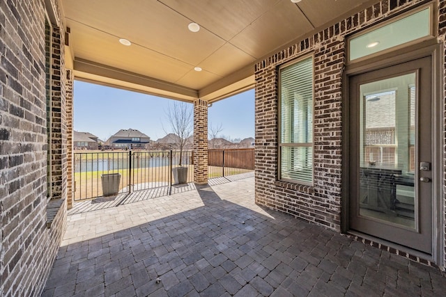 view of patio with a water view and fence