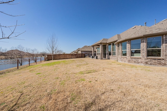 view of yard with a water view and a fenced backyard