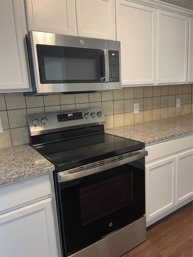 kitchen with decorative backsplash, white cabinetry, stainless steel appliances, and dark wood-type flooring