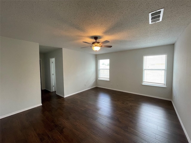 unfurnished room with dark wood-style flooring, visible vents, ceiling fan, and baseboards