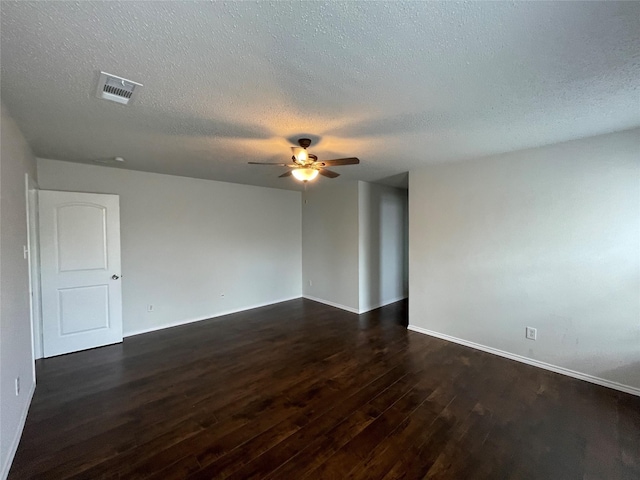 empty room featuring baseboards, visible vents, ceiling fan, dark wood-style flooring, and a textured ceiling