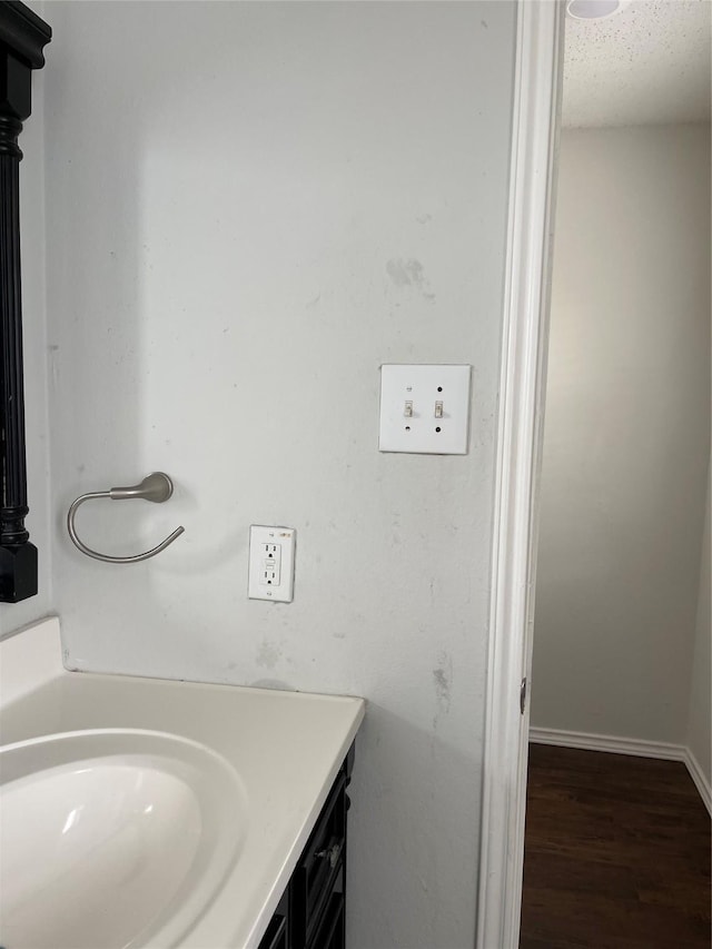 bathroom featuring a textured ceiling, wood finished floors, vanity, and baseboards