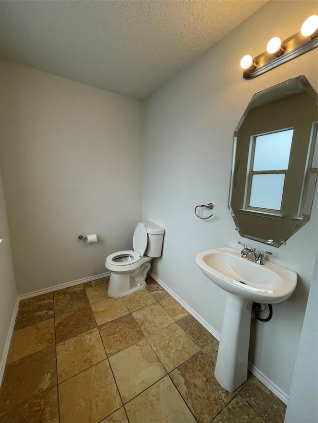 bathroom featuring toilet, baseboards, and a textured ceiling