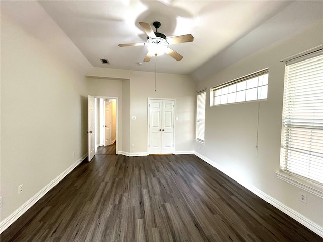 unfurnished bedroom featuring dark wood-style flooring, a closet, visible vents, ceiling fan, and baseboards